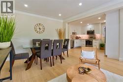Open-concept living area featuring light wood-finish flooring, recessed lighting, and crown molding - 