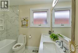 Bathroom featuring a white vanity with dual integrated sinks, polished chrome fixtures, and a large mirror - 