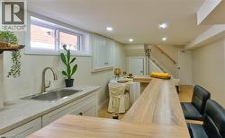 Lower-level space featuring a contemporary wood-finish bar, recessed lighting, and light wood-finish flooring - 