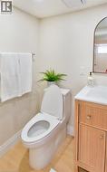 Powder room featuring a white toilet, light wood-finish flooring, and a vanity with a white countertop and integrated sink - 