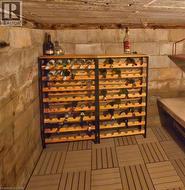 Basement space featuring light-toned wood-finish flooring tiles, exposed cinder block walls, and a wood-beamed ceiling - 