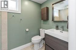 Contemporary bathroom featuring a floating wood-finish vanity with an integrated sink, a rectangular framed mirror, and a wall-mounted wood-finish cabinet - 