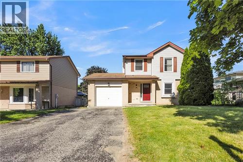 Two-story property featuring a red front door, attached single-car garage, and a lush green lawn - 127 Acorn Crescent, London, ON 