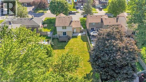Expansive rear yard featuring a large grass area, mature trees, and a wooden deck - 127 Acorn Crescent, London, ON 