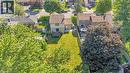 Expansive rear yard featuring a large grass area, mature trees, and a wooden deck - 127 Acorn Crescent, London, ON 