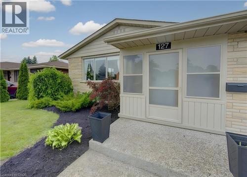 Brick veneer exterior featuring a covered entry, established landscaping, and a concrete pathway - 127 Strathcona Crescent, Kitchener, ON 