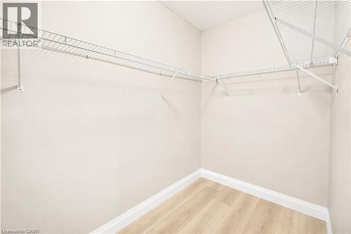 Walk-in closet featuring light wood-finish flooring, white baseboards, and wire shelving on multiple walls - 129 St George Street, Kitchener, ON 