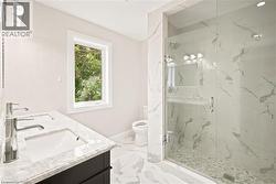 Contemporary bathroom featuring a spacious glass-enclosed shower with pebble flooring and large-format wall tiles - 