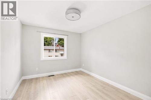 Bright room featuring light wood-finish flooring, neutral wall paint, and white baseboards - 129 St George Street, Kitchener, ON 