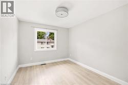 Bright room featuring light wood-finish flooring, neutral wall paint, and white baseboards - 