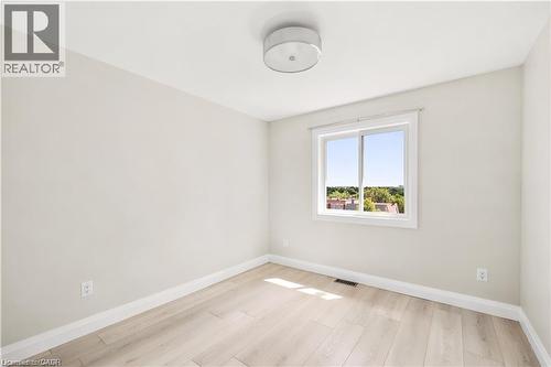 Light-filled room featuring wood-finish flooring, neutral wall tones, and a window with white trim - 129 St George Street, Kitchener, ON 
