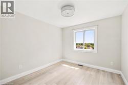 Light-filled room featuring wood-finish flooring, neutral wall tones, and a window with white trim - 