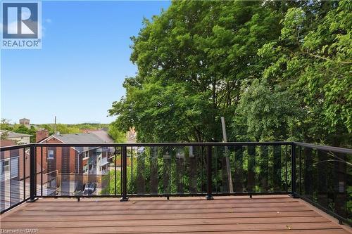 Expansive outdoor deck featuring wood-finish flooring and a black metal railing with glass panels - 129 St George Street, Kitchener, ON 