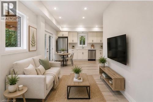 Open-concept living area featuring light wood-finish flooring, recessed lighting, and a white wall-mounted entertainment console - 129 St George Street, Kitchener, ON 