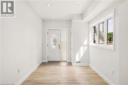 Entryway featuring a decorative glass front door, side-light, recessed lighting, wood-finish flooring, and a large window - 129 St George Street, Kitchener, ON 