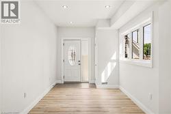 Entryway featuring a decorative glass front door, side-light, recessed lighting, wood-finish flooring, and a large window - 