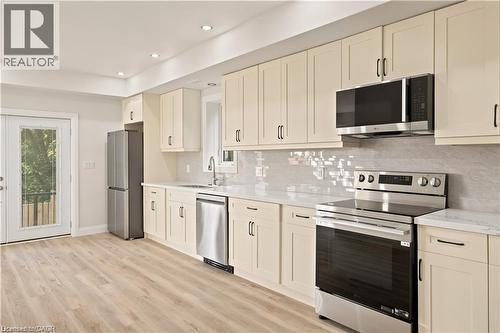 Kitchen featuring light wood-finish flooring, recessed lighting, and a white tile backsplash - 129 St George Street, Kitchener, ON 