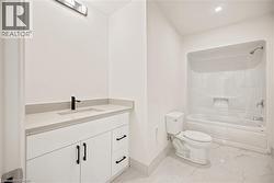 Bathroom featuring white cabinetry with matte black hardware, a light-toned countertop with integrated sink, a matte black faucet, and a combination tub/shower unit - 