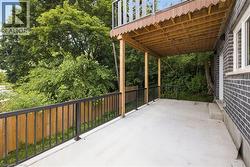 Spacious covered concrete patio with black metal railings and a wooden privacy fence - 