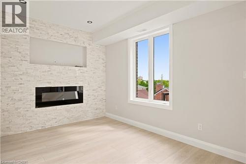 Living space featuring a stacked stone accent wall with an integrated linear electric fireplace and built-in media niche - 129 St George Street, Kitchener, ON 