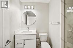 Contemporary bathroom featuring a white vanity with quartz-style countertop, undermount sink, and black hardware - 