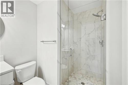 Walk-in shower featuring a frameless glass enclosure, a rain shower head, and natural stone tile finishes - 131 St George Street, Kitchener, ON 