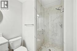 Walk-in shower featuring a frameless glass enclosure, a rain shower head, and natural stone tile finishes - 