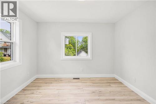 Bright interior space featuring light wood-finish flooring, white baseboards, and two windows with white trim - 131 St George Street, Kitchener, ON 