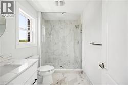Full bathroom featuring a glass-enclosed shower with a tiled interior, a vanity with an integrated sink, and white marble-look flooring - 