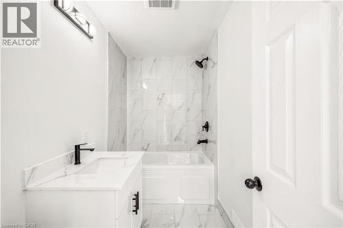 Bathroom featuring a white vanity with an integrated sink and quartz-finish countertop, matte black faucet, and a wall-mounted light fixture - 131 St George Street, Kitchener, ON 