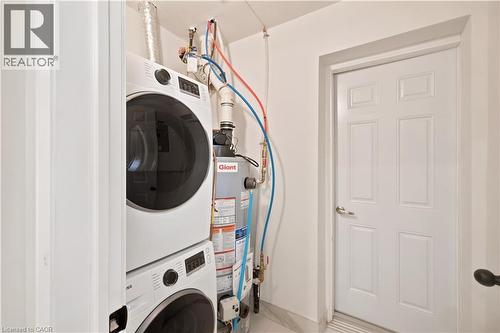Dedicated laundry area featuring a stacked washer and dryer, adjacent to a utility door - 131 St George Street, Kitchener, ON 