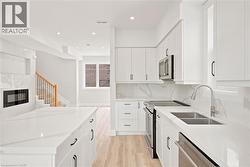 Modern kitchen featuring white shaker cabinetry, stainless steel appliances, dual basin sink, and ample white countertops - 
