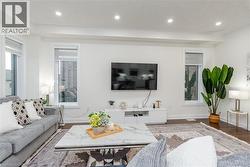 Living room featuring warm wood-finish flooring, recessed lighting, and bright white walls - 