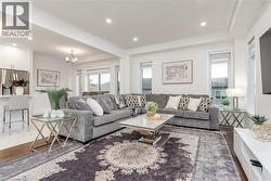 Open-concept living area with recessed lighting, large windows, and wood-finish flooring extending into the background - 