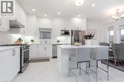 Modern kitchen featuring white cabinetry, stainless steel appliances, a white subway tile backsplash, and a central island with countertop seating - 