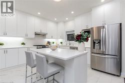 Modern kitchen featuring white cabinetry, a white countertop island, stainless steel appliances, recessed lighting, and tile flooring - 