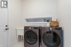 Dedicated laundry area featuring a utility sink, a horizontal window, and panel door with bronze hardware - 