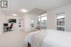 Spacious carpeted room featuring multiple large windows with roller shades, a glass-paneled door leading to an outdoor balcony, and recessed ceiling lighting - 