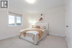 Light-toned bedroom featuring wall-to-wall carpeting, a multi-pane window, white trim, and a paneled interior door - 