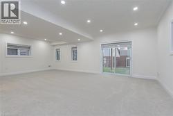 Spacious room featuring light-toned carpeting, recessed ceiling lighting, and multiple windows - 