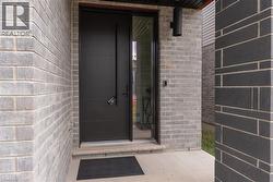 Modern exterior featuring a dark entry door with horizontal detailing, a full-length sidelight, and a contemporary wall sconce - 