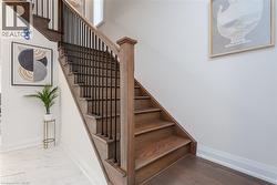 Staircase featuring wood-finish treads and risers, black metal balusters, and a matching wood-finish newel post and handrail - 