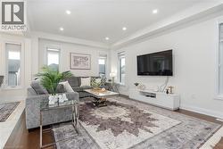 Spacious living area featuring dark wood-finish flooring, recessed lighting, and multiple windows - 