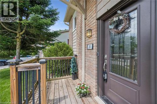Brick facade featuring a recessed entry, wood deck, and wood railing with black spindles - 24 Byton Lane, Cambridge, ON 