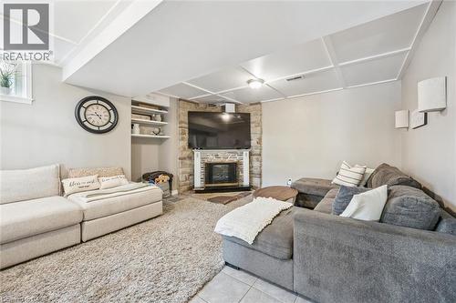 Living area featuring a corner-set stone fireplace, built-in shelving, a coffered ceiling, and a window - 24 Byton Lane, Cambridge, ON 