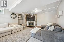Living area featuring a corner-set stone fireplace, built-in shelving, a coffered ceiling, and a window - 