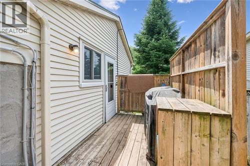 Rear wooden deck space featuring a privacy fence, wood-paneled siding, and an exterior door - 24 Byton Lane, Cambridge, ON 