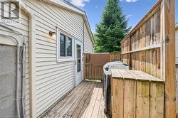 Rear wooden deck space featuring a privacy fence, wood-paneled siding, and an exterior door - 