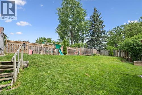 Spacious rear yard with a sloped, grass lawn and wood fencing - 24 Byton Lane, Cambridge, ON 