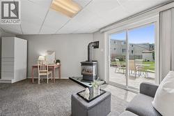 Spacious room with sliding glass doors opening to a wood deck, featuring a floor-standing fireplace, built-in white cabinetry, and wall-to-wall carpeting - 